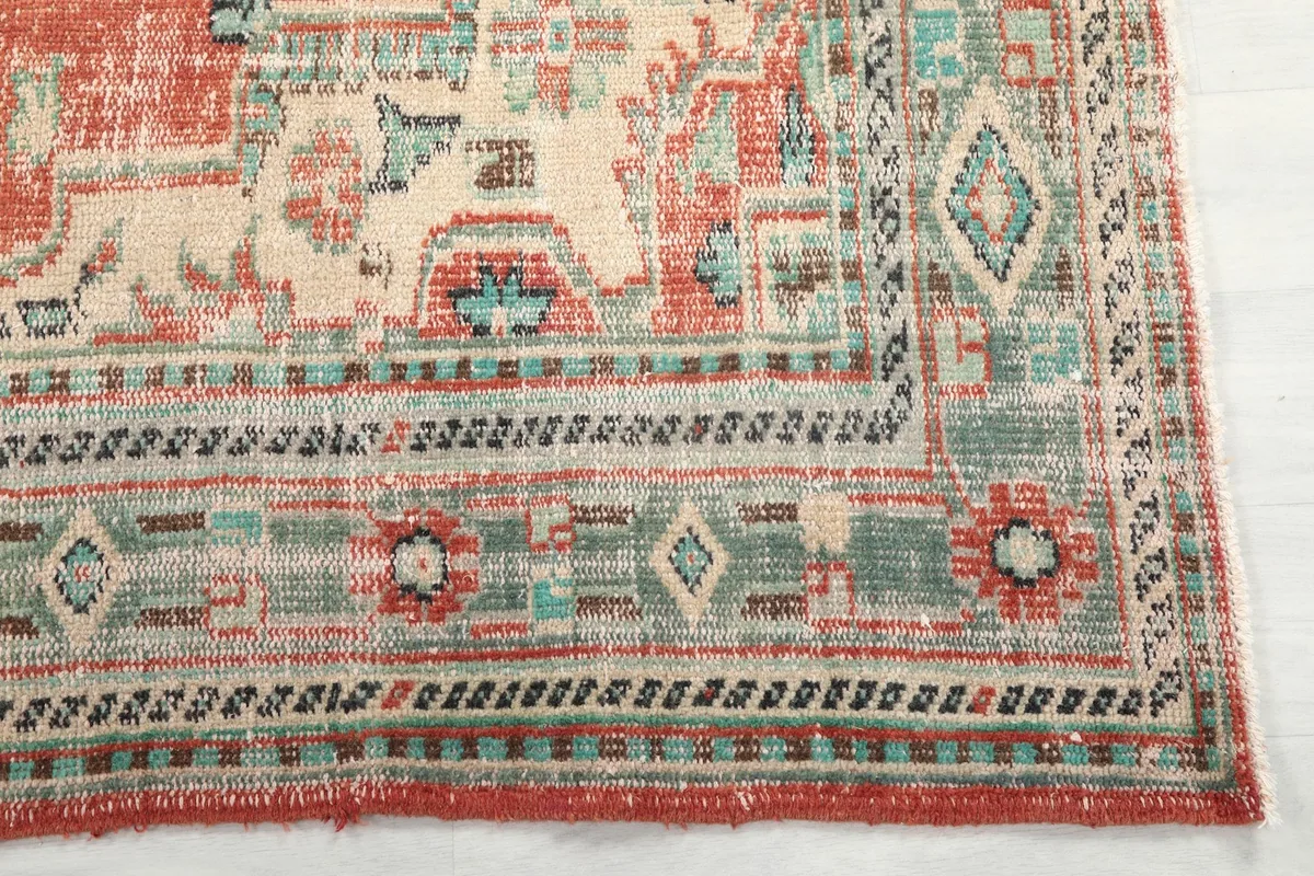 Detailed corner view of the rug's beige and green geometric border design
