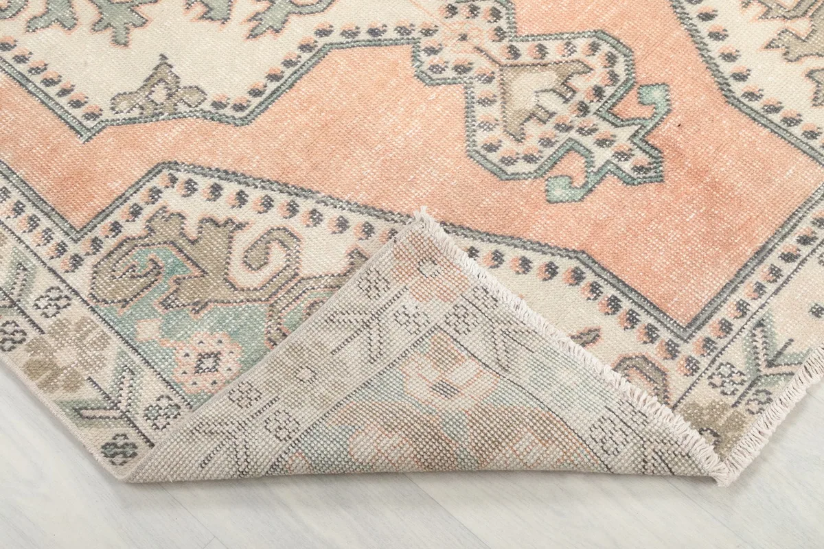 Corner of the rug folded back to reveal the back of the hand-knotted cotton foundation