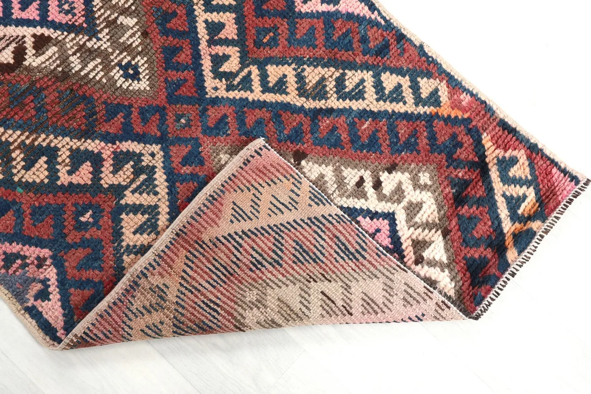 Corner of the rug folded back to reveal the cotton foundation and the reverse side of the hand-knotted wool pile.