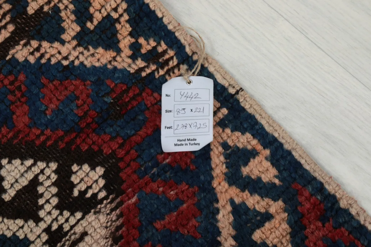 Detail of the rug's corner with a tag showing size information and origin, against the geometric pattern.
