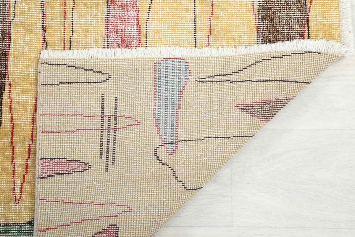 Underside of the rug's corner, revealing the hand-knotted cotton foundation and fringe
