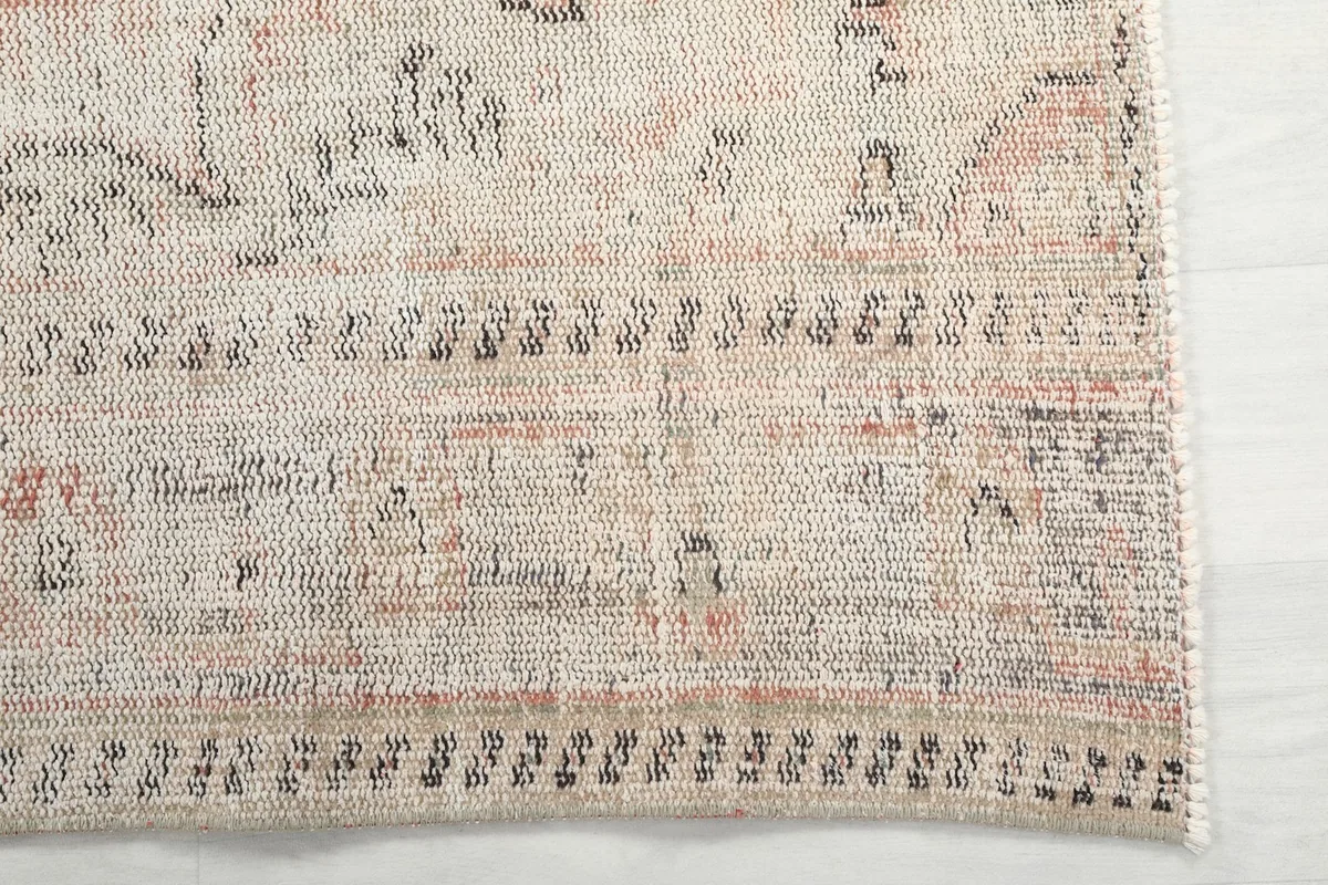 Detail of the rug's border, showcasing the hand-knotted wool texture and subtle patterns.