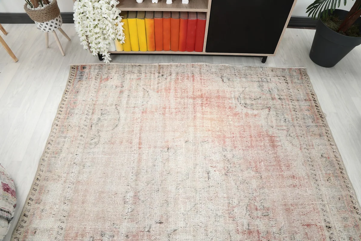 Overhead view of the rug, displaying its rectangular shape and faded rose and beige palette.