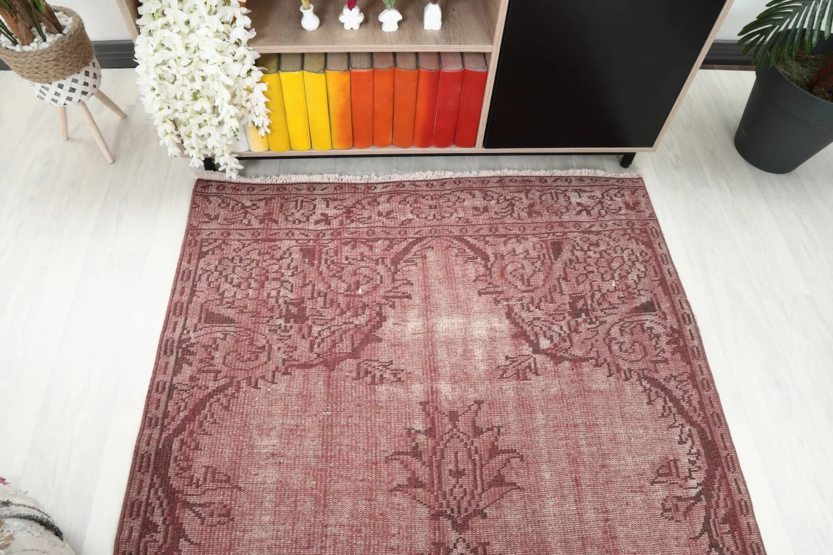 Overhead view focusing on one end of the rose vintage rug with its border