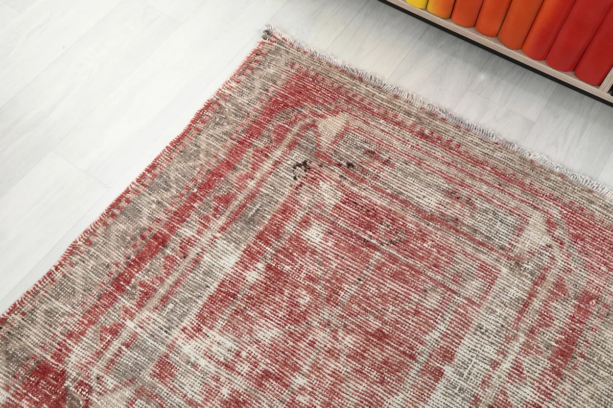Corner view of the runner rug highlighting its faded rose and gray color palette
