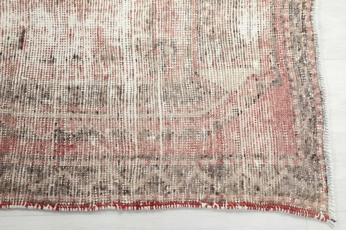 Detail of the rug's border showing faded gray and tan tribal motifs and low pile