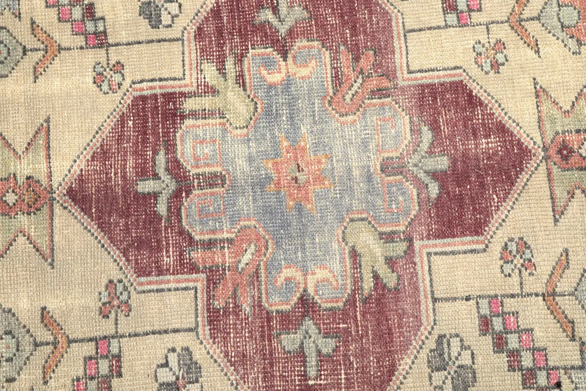 Close-up of the medallion's intricate design, showing faded rose, gray, and brown tones