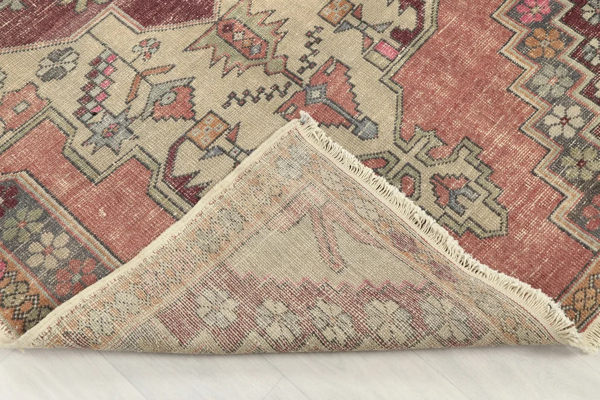 Folded corner showing the rug's reverse side, revealing the cotton foundation and knotting