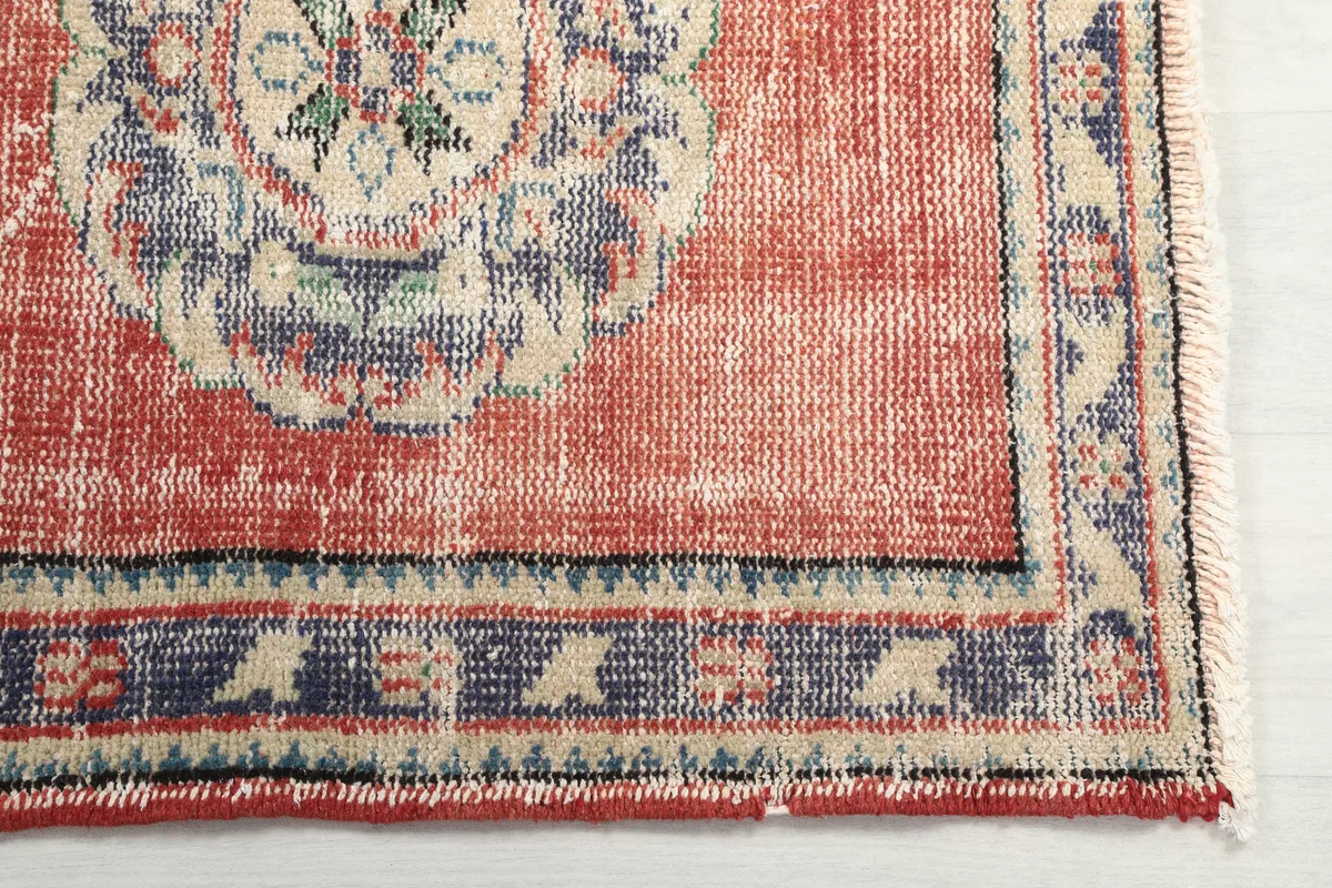 Detailed view of the Faded Rust Medallion Anatolian Runner's border and fringe, showcasing the navy and beige patterns.