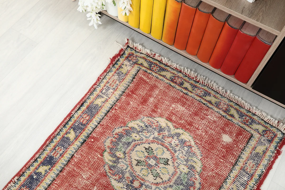 Angled view of the Faded Rust Medallion Anatolian Runner's end, showing its placement next to a bookshelf.