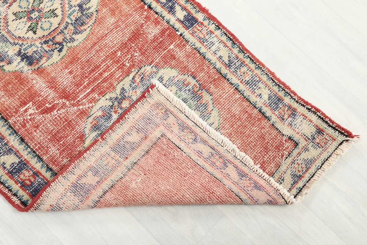 Corner of the Faded Rust Medallion Anatolian Runner folded back, revealing the reverse side and foundation.