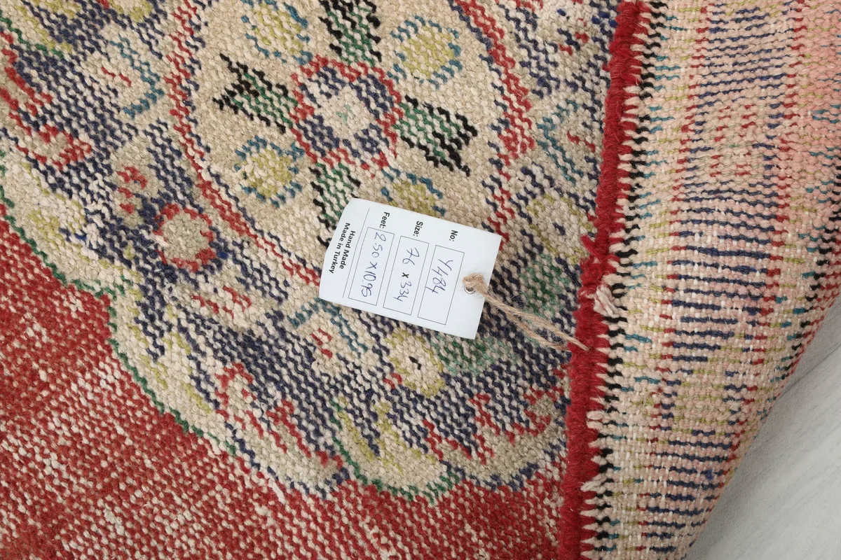 Detail of the Faded Rust Medallion Anatolian Runner with a tag, showing the rug's label and weave.