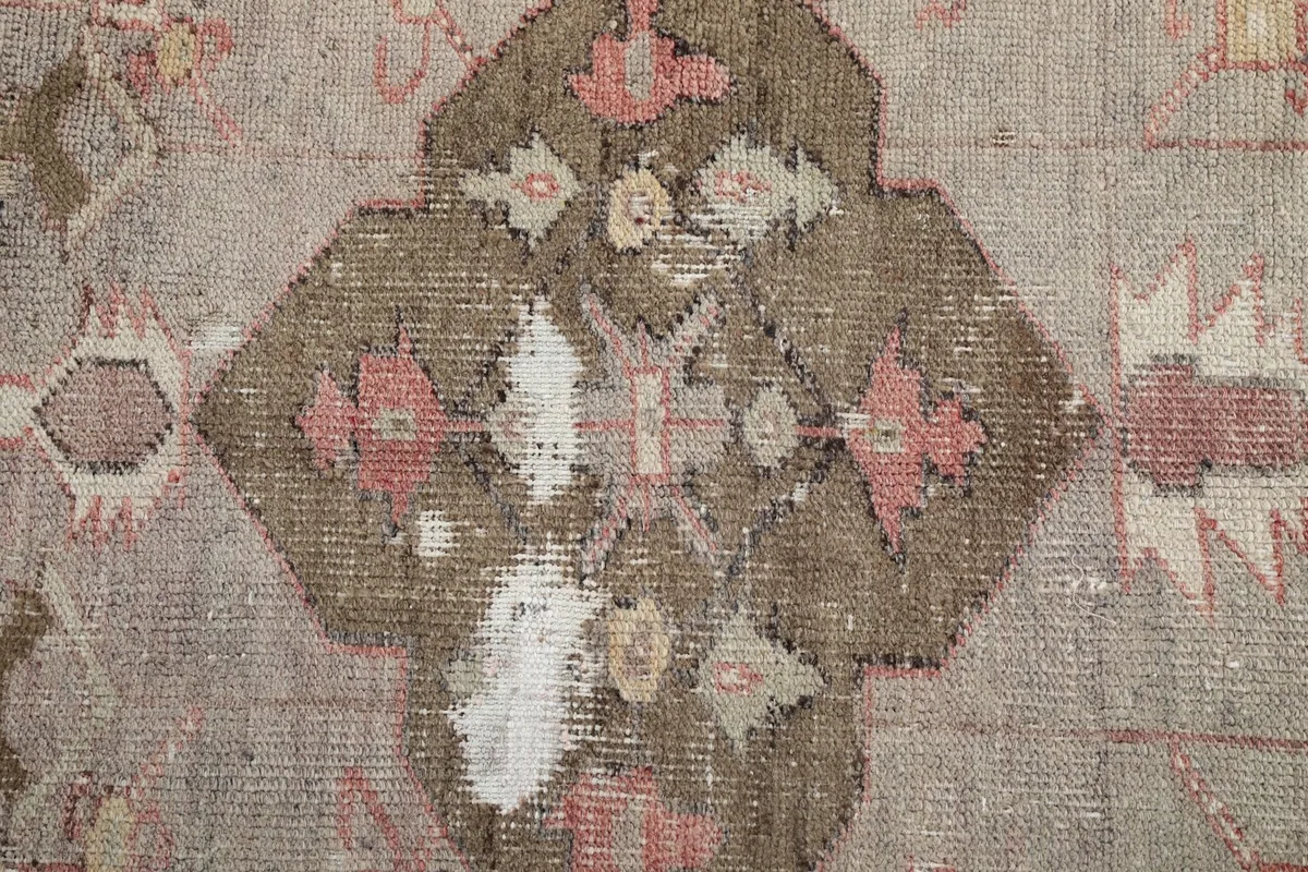 Close-up of the rug's central medallion, highlighting the intricate geometric and floral details and color variations.
