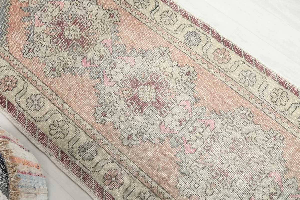 Overhead angle shot of the runner rug, focusing on the central geometric medallions and faded rust field.