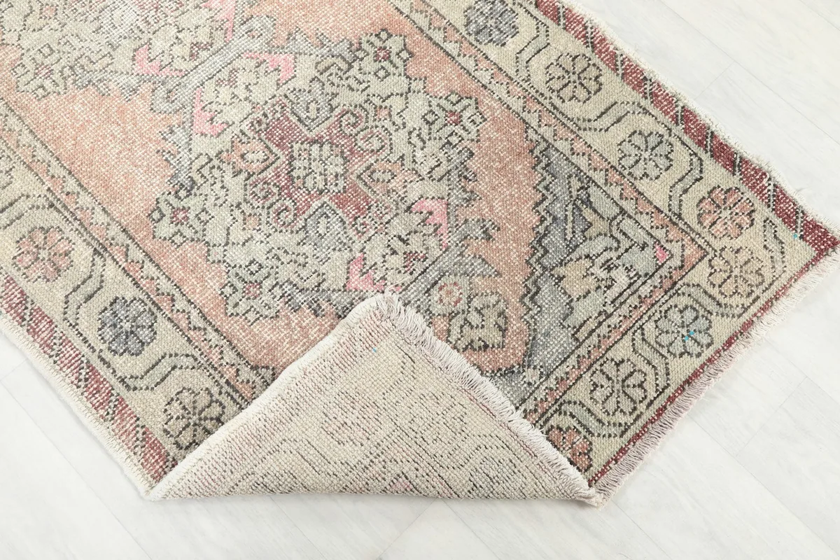 Corner of the rug folded back to show the low wool pile and hand-knotted cotton foundation.
