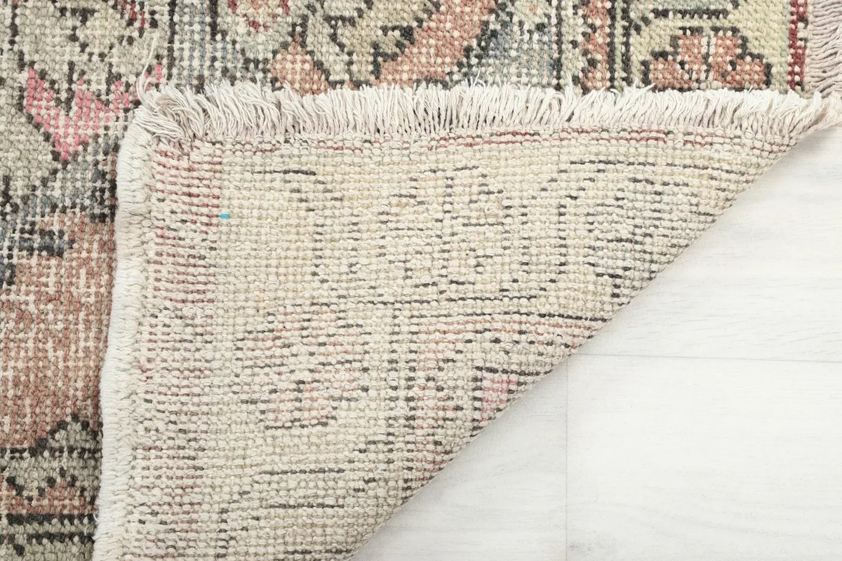 Close-up of the rug's underside and fringe, revealing the hand-knotted construction.