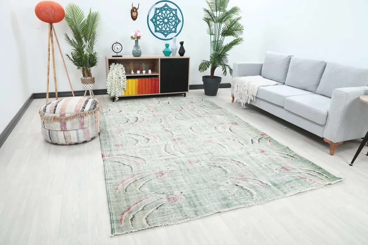 Angle view of the green vintage rug in a living room, showing its placement relative to a sofa and ottoman.