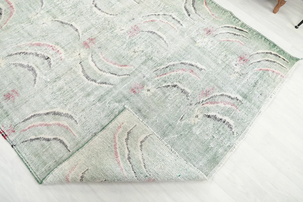The green vintage rug with a corner folded over, illustrating its flexibility and thickness.