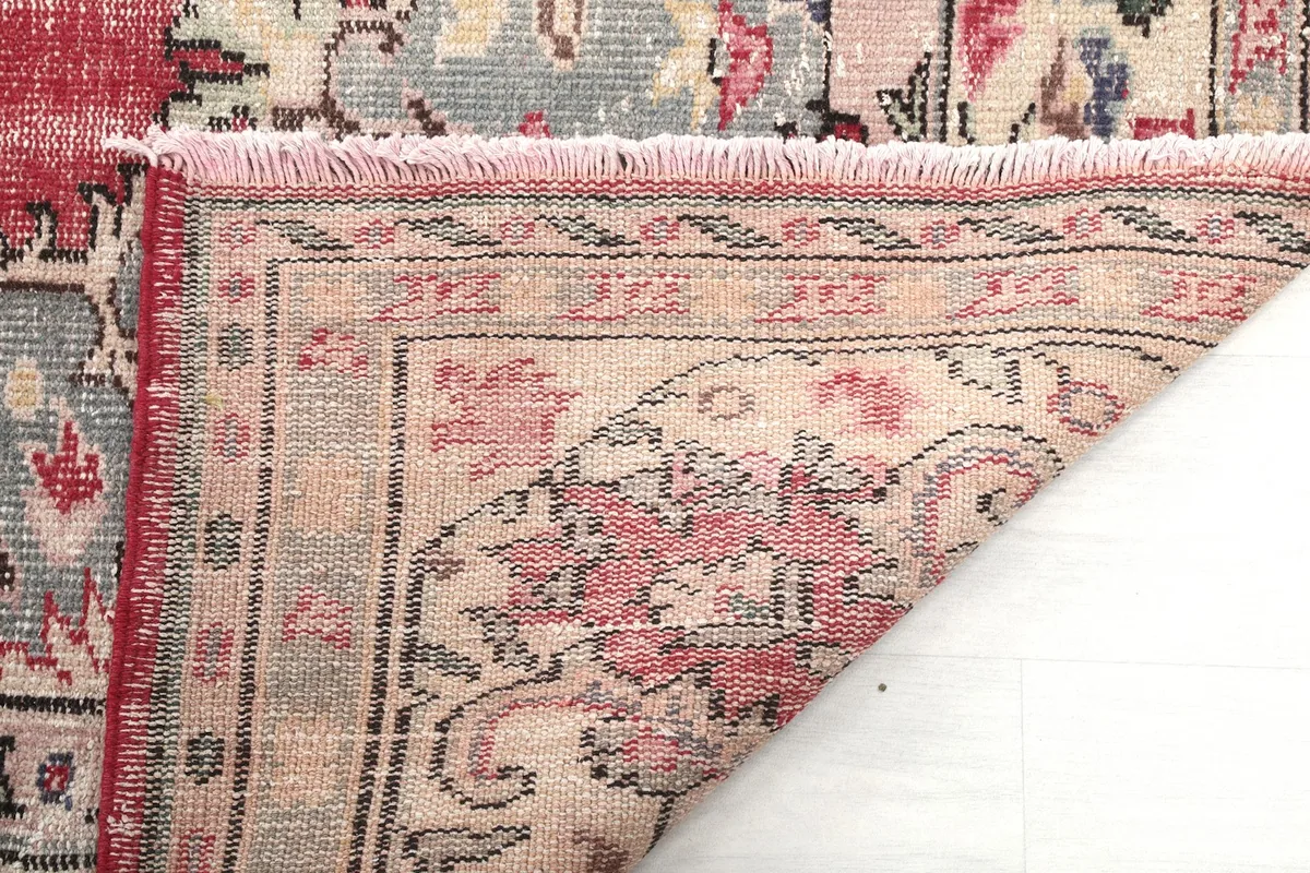 Underside view of the rug's corner, showing the hand-knotted construction and fringe