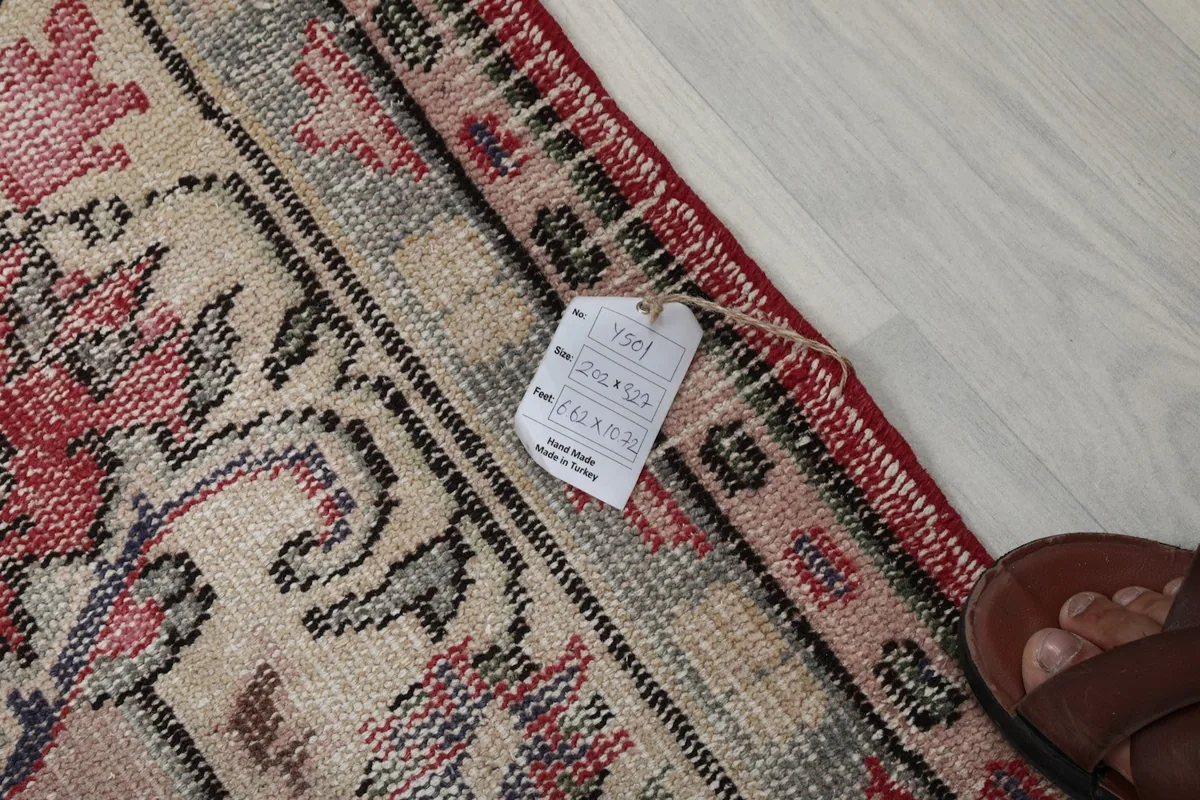 Close-up of the rug's edge with a product tag, showing the weave and a foot for scale