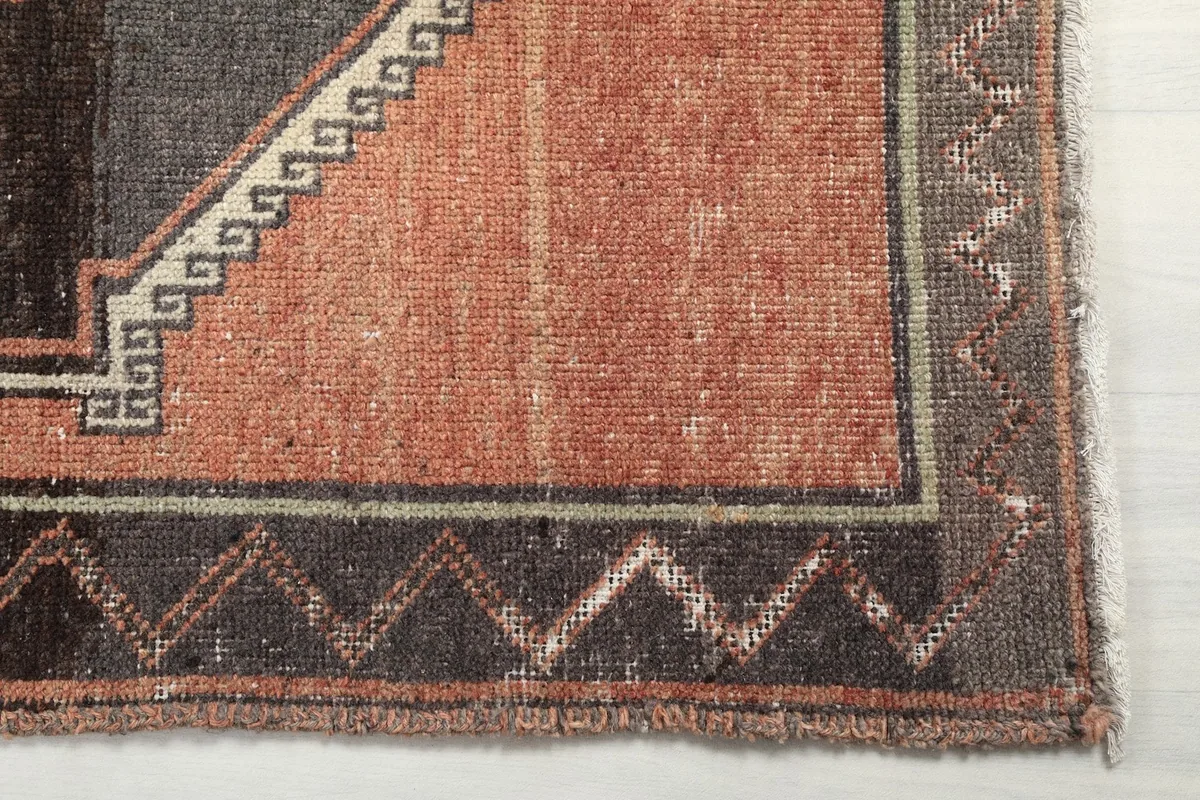 Detailed view of the rug's end, showing the outer border with zigzag patterns and subtle wear.
