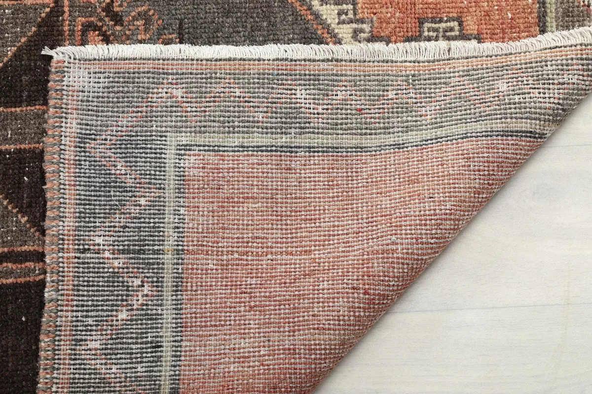 Underside of the rug's corner, showing the tightly woven cotton foundation and hand-knotted construction.