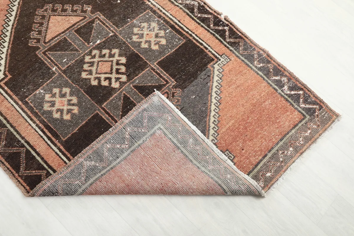 Corner of the rug folded back, revealing the hand-knotted wool pile and cotton foundation.