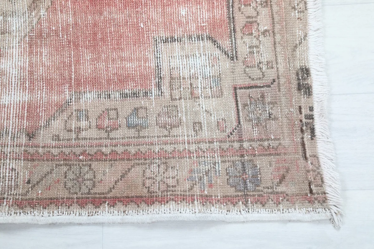 Close-up of the rug's border pattern with subtle blue and brown accents on a beige field