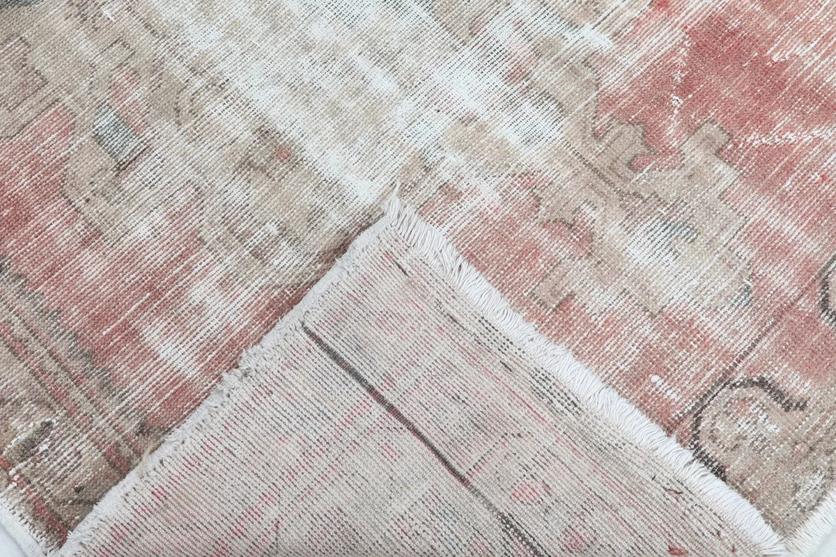 View of the rug's corner folded back, revealing the hand-knotted cotton foundation