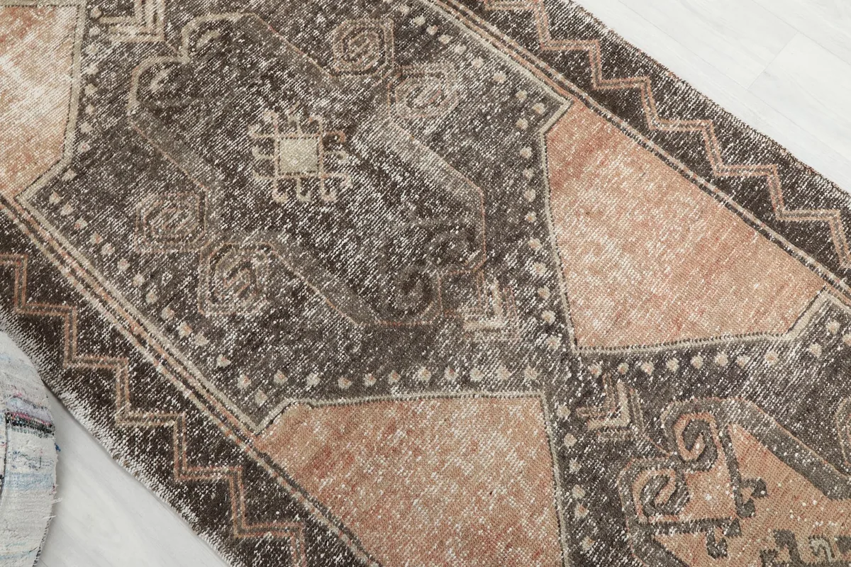 Overhead angled view of the rug's central design, showcasing the intricate charcoal and rust patterns