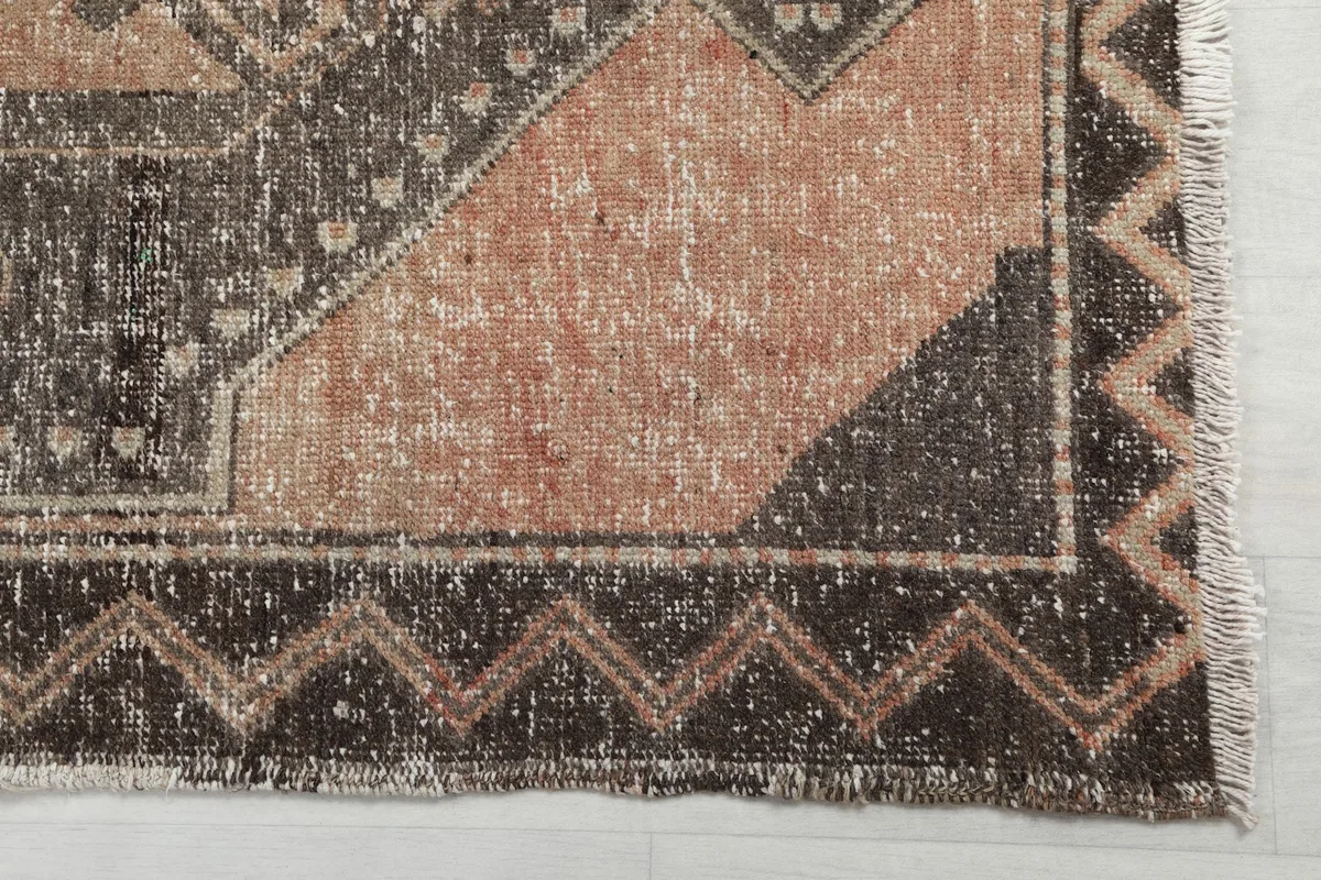 Close-up of a corner of the runner rug, highlighting the zigzag border and faded rust tones