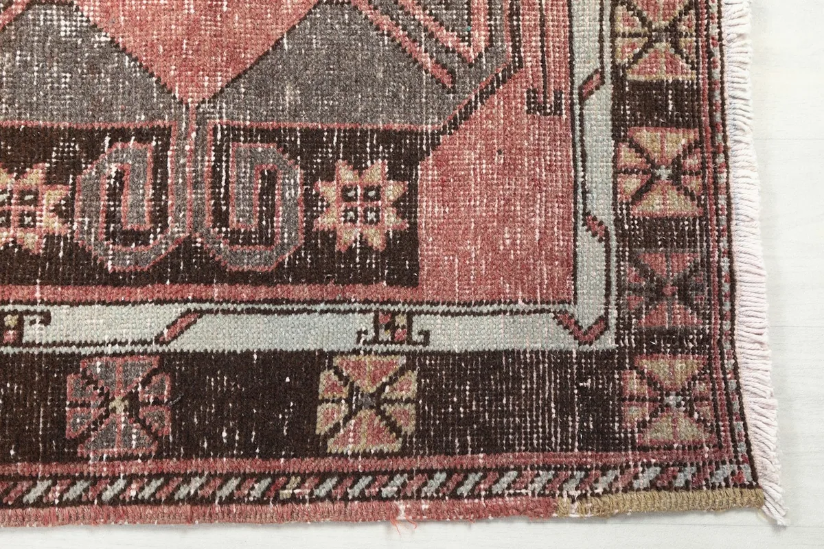 Close-up detail of the rug's border and corner, highlighting the brown and beige patterns