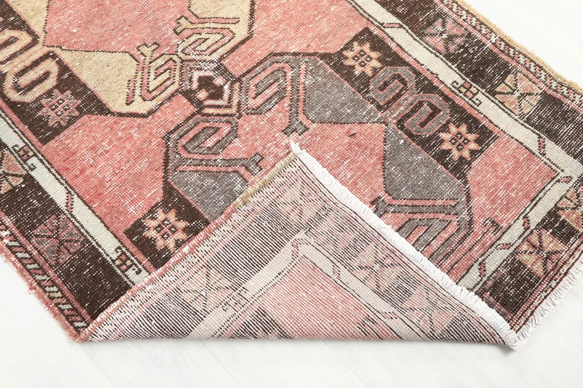 Corner of the rug folded back to reveal the back of the hand-knotted wool pile