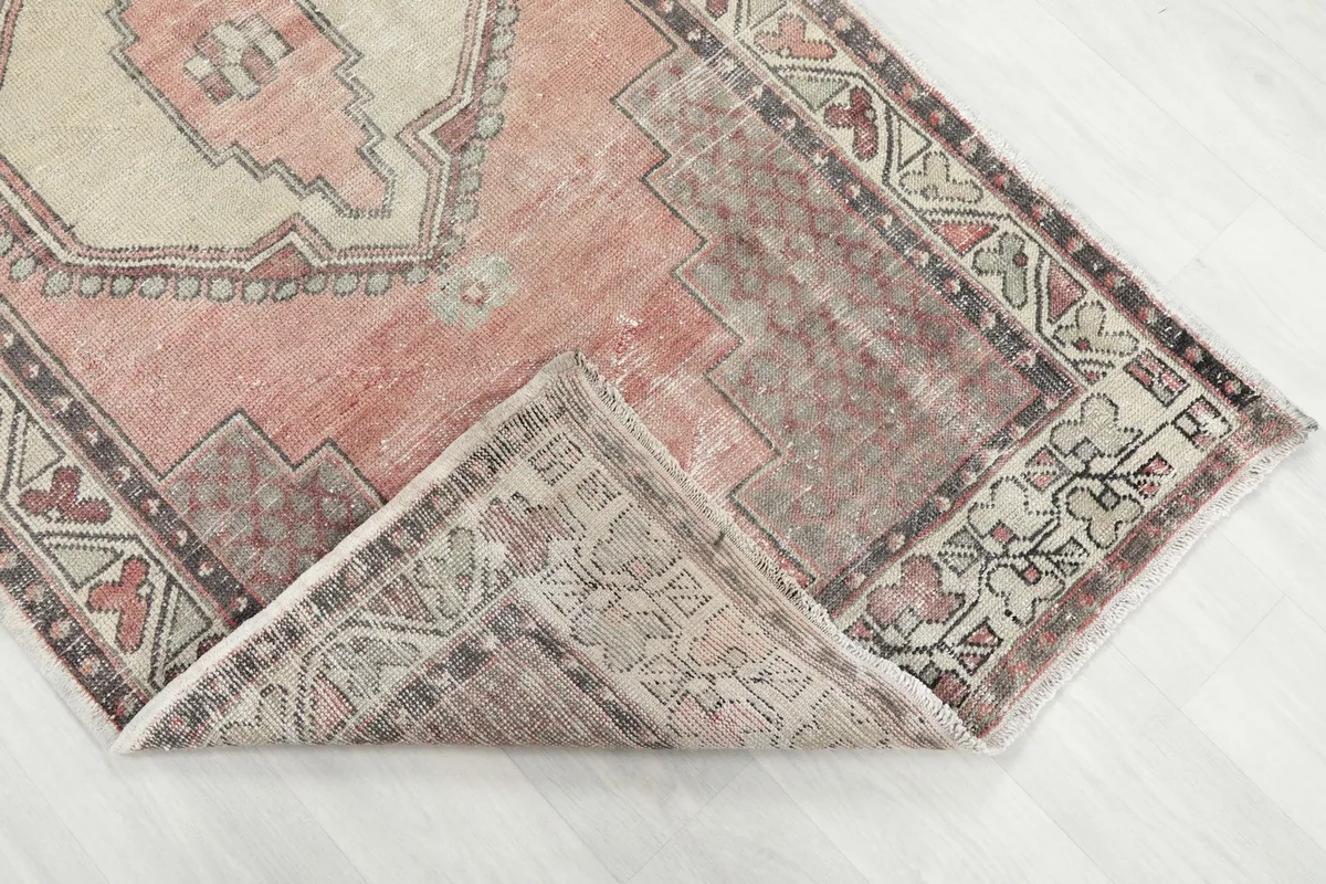 Corner of the rug folded back to show the pile and distressed texture