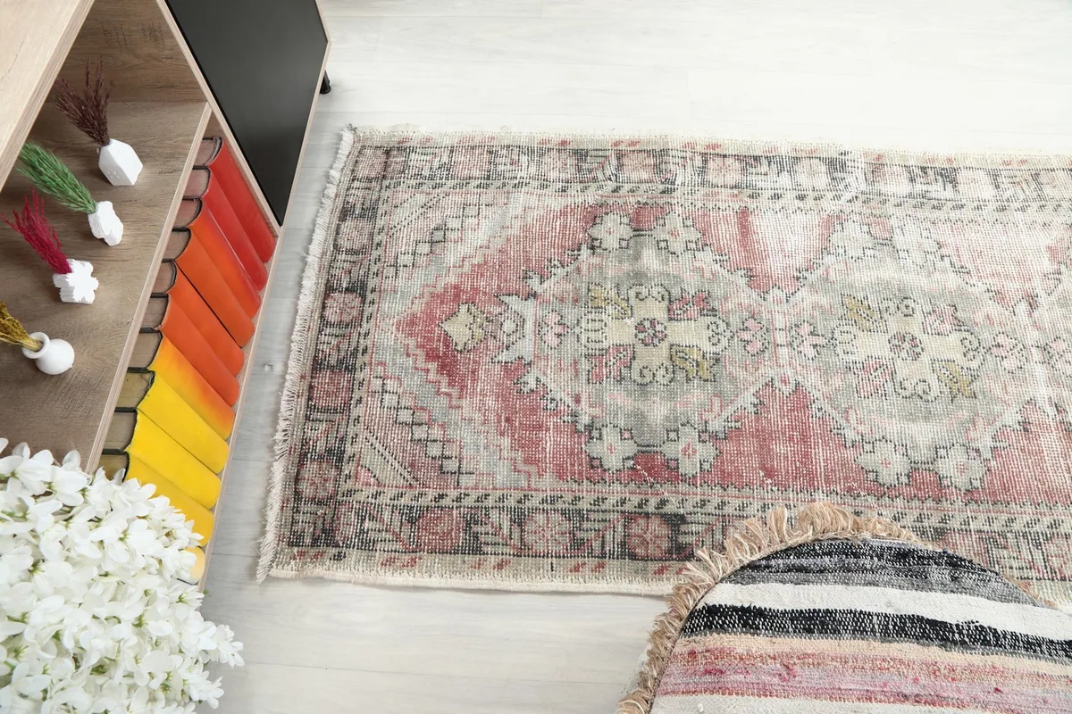 Diagonal overhead shot of the rug, emphasizing the faded rose field and the gray tribal patterns.