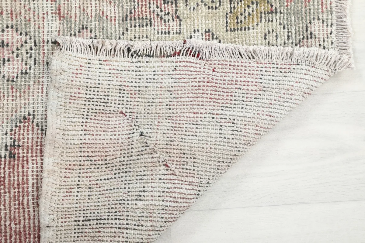 Close-up of the rug's reverse side, illustrating the tightly woven cotton foundation and short fringes.