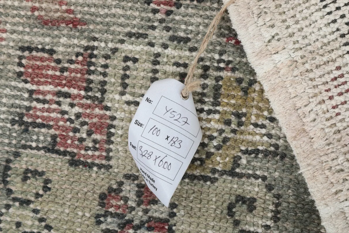 Detail showing the product tag with rug number and size measurements, attached to the corner of the rug.