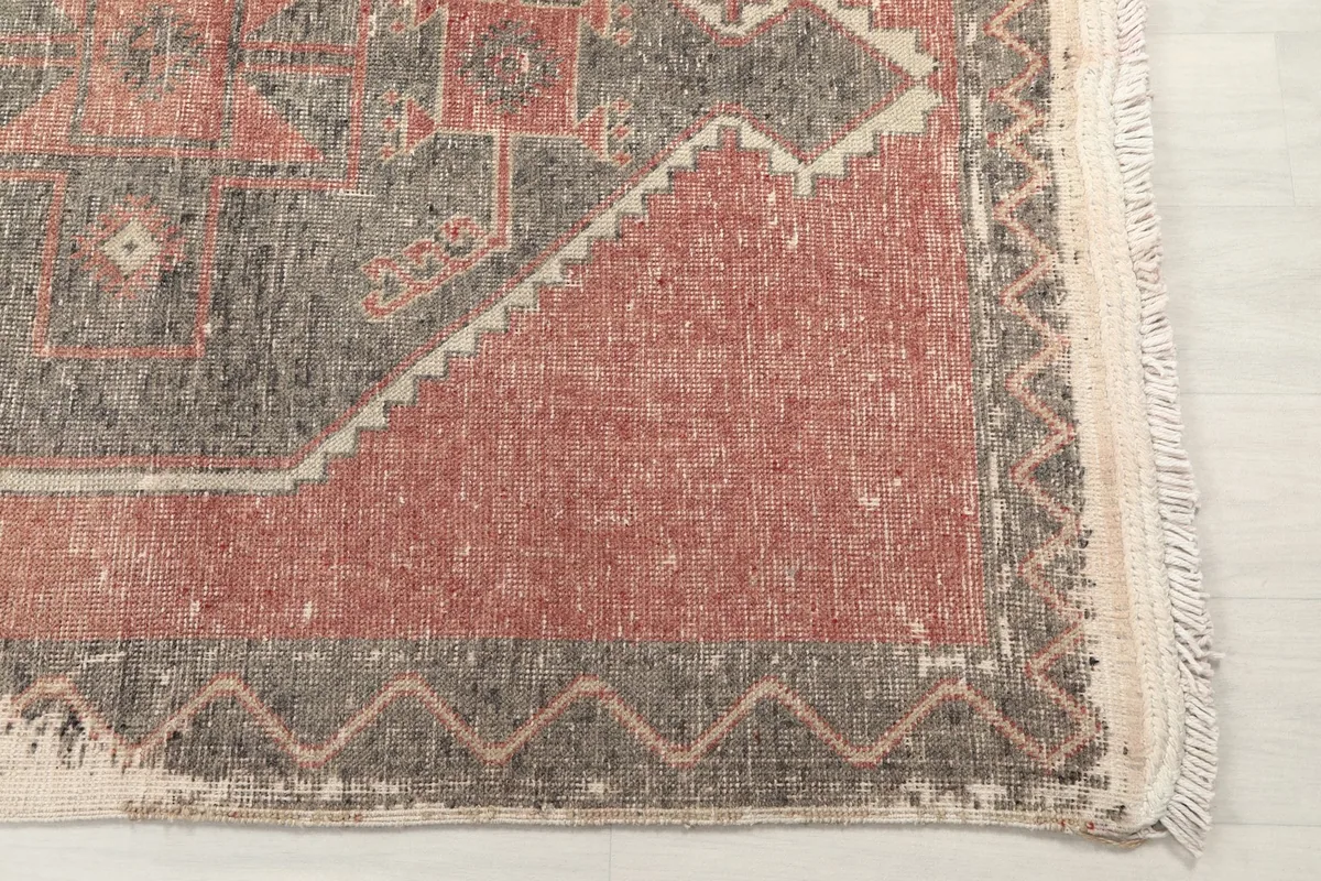 Close-up of the rug's end, showing the outer border with a zigzag pattern and the short fringe.