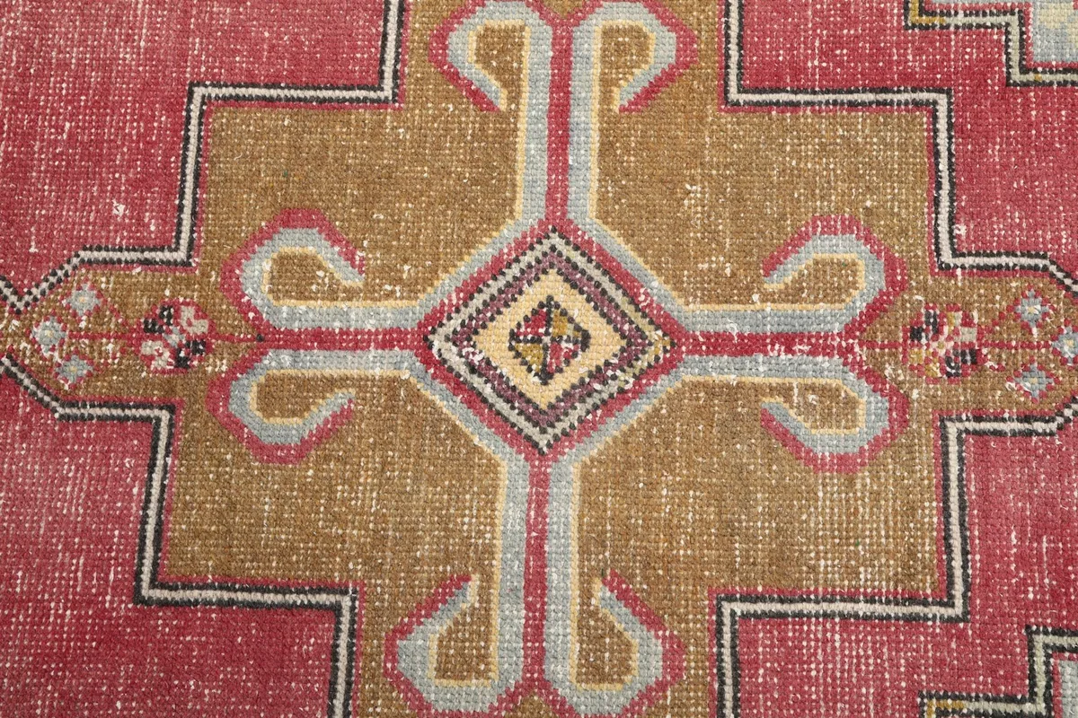 Close-up of the central gold geometric medallion motif on the rose field