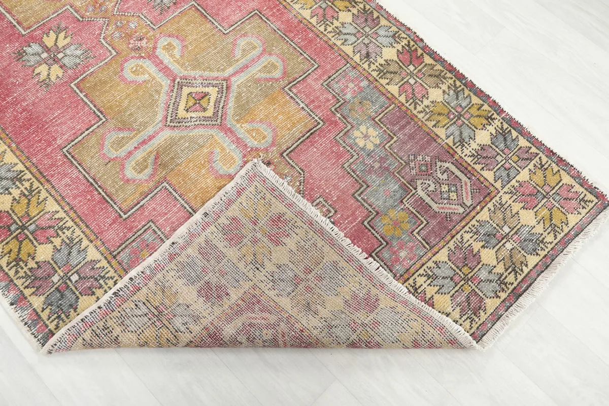 Corner of the rug folded to reveal the hand-knotted cotton foundation and pile backing