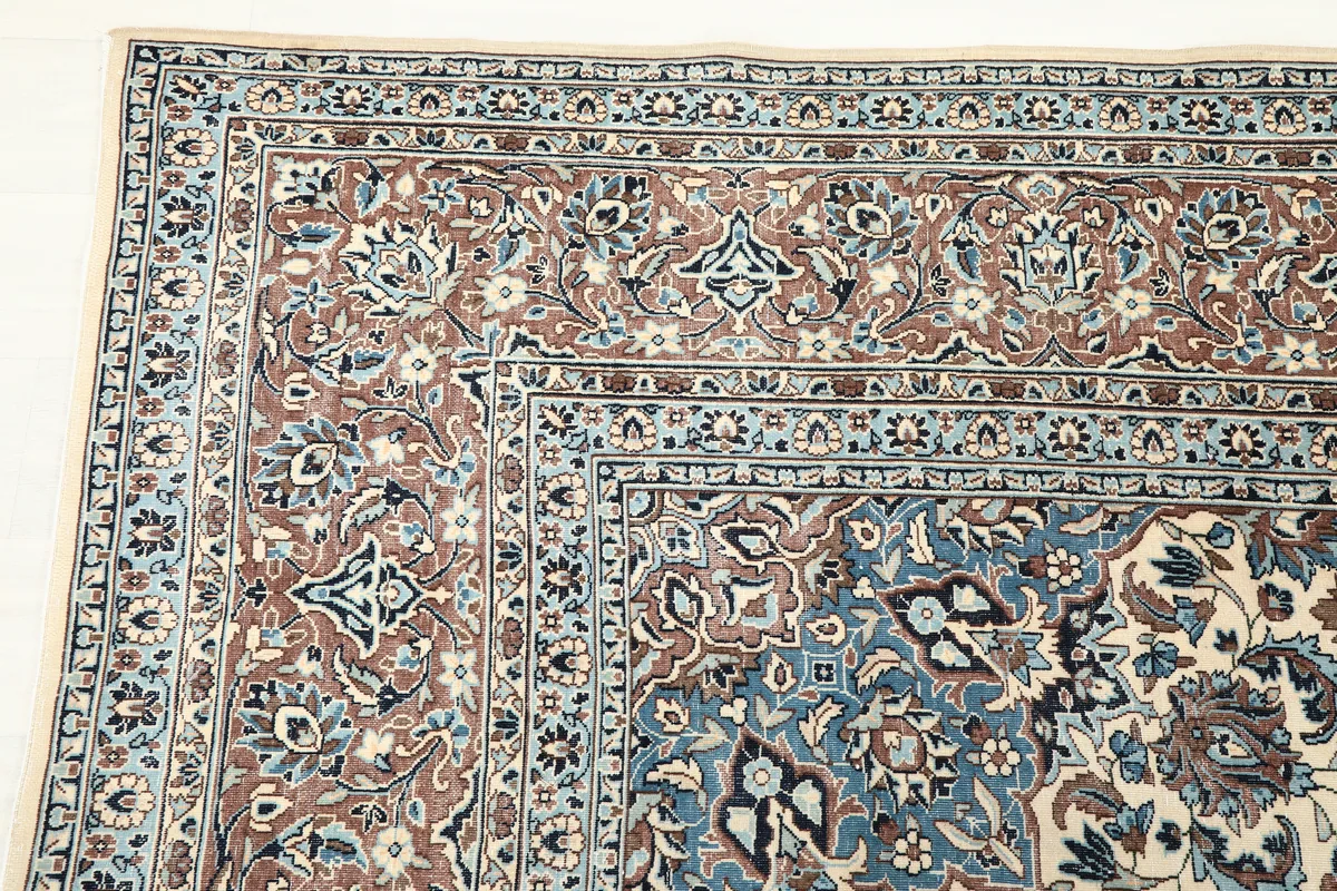 Detail of the corner design of the Ivory Floral Medallion Anatolian Rug, showing blue and brown borders
