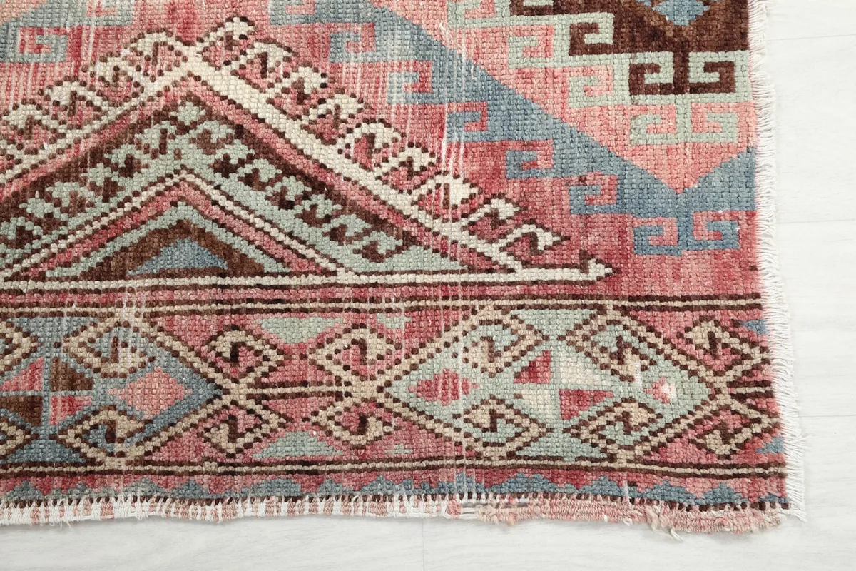Detailed view of the intricate geometric border and field patterns on the vintage rug
