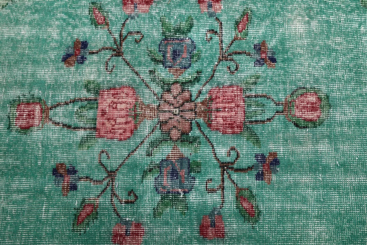 Close-up of the intricate floral design within the rug's green medallion