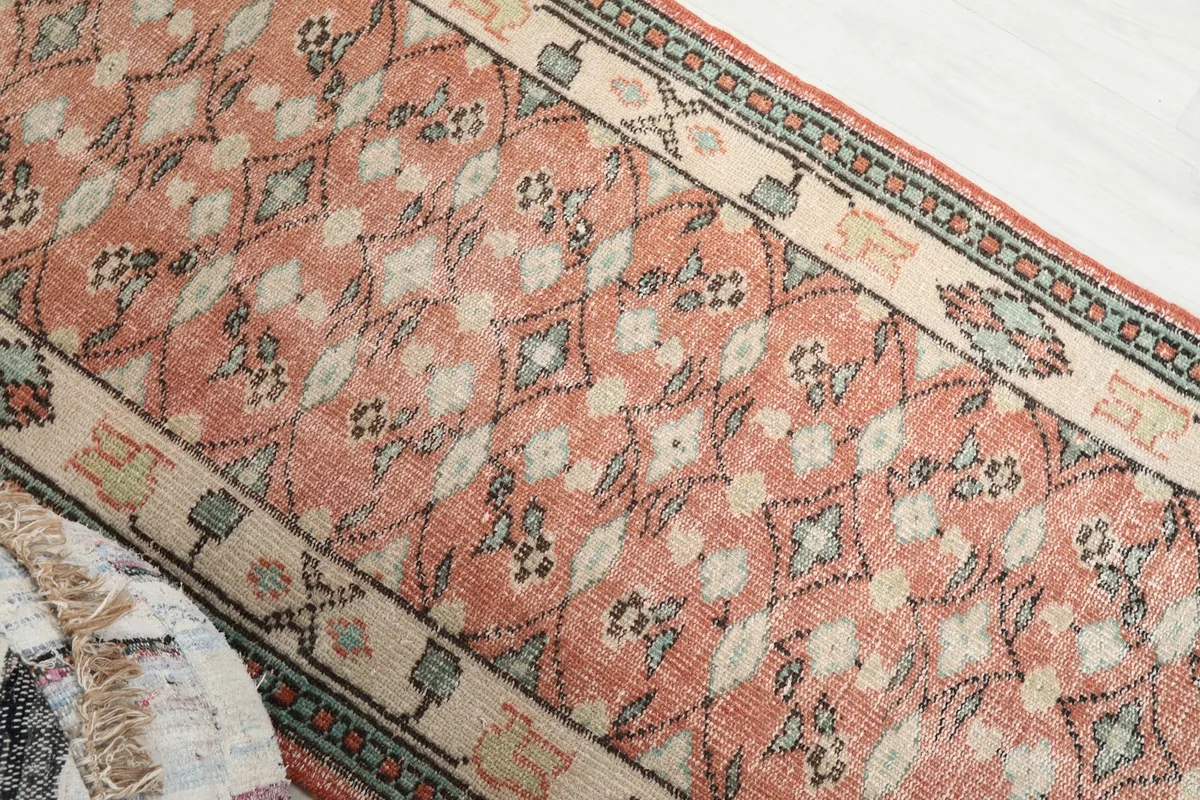 Overhead angled view showing the full width of the rose geometric runner rug and its colors.