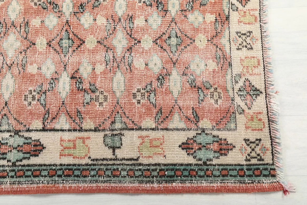 Detailed view of the rose field and ivory border with blue and gray accents at one end of the rug.