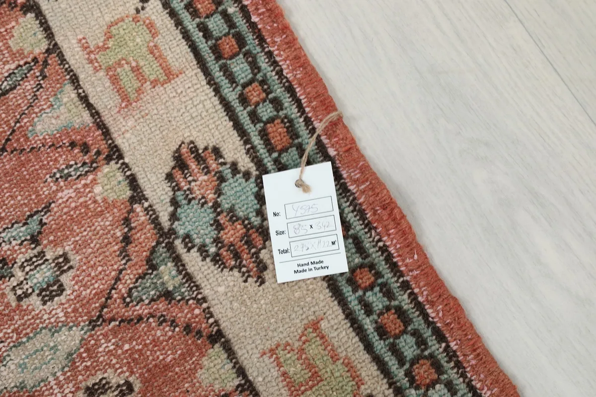 Corner of the rug with a product tag, showing the hand-knotted wool pile and cotton foundation.