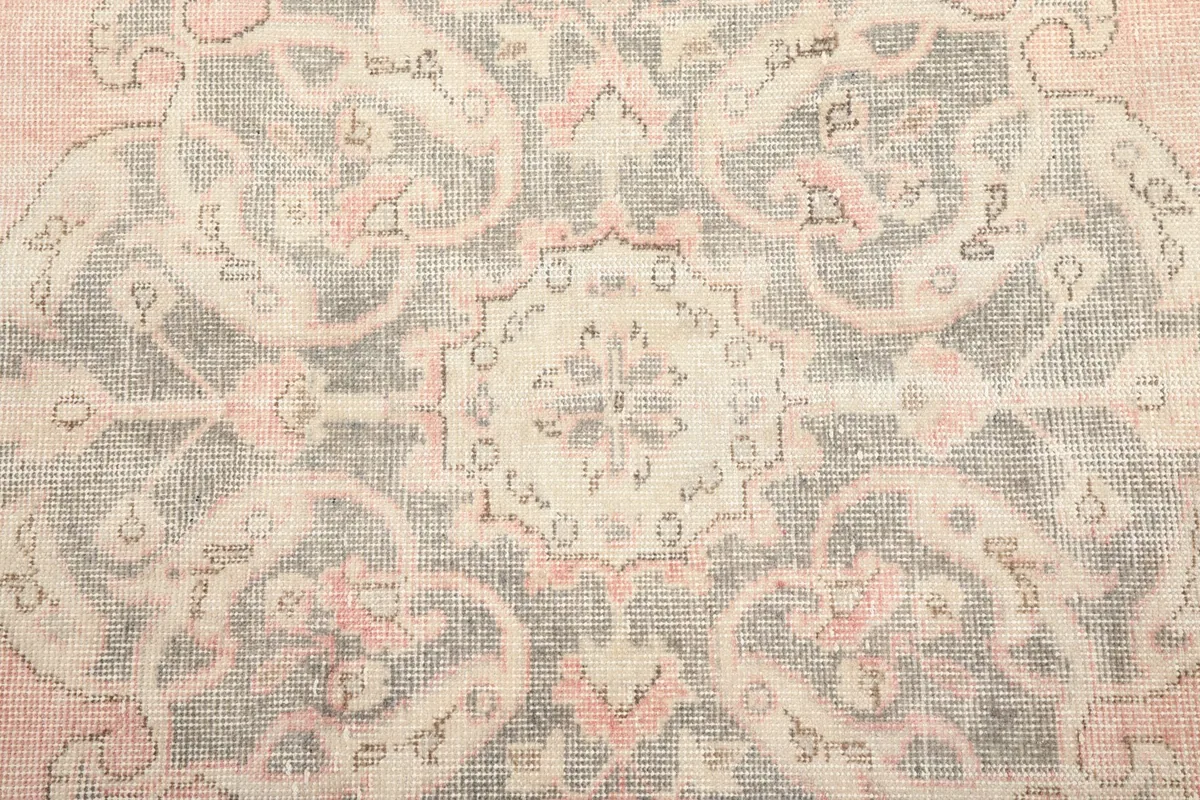 Detailed overhead view of the intricate gray and rose floral motifs within the medallion