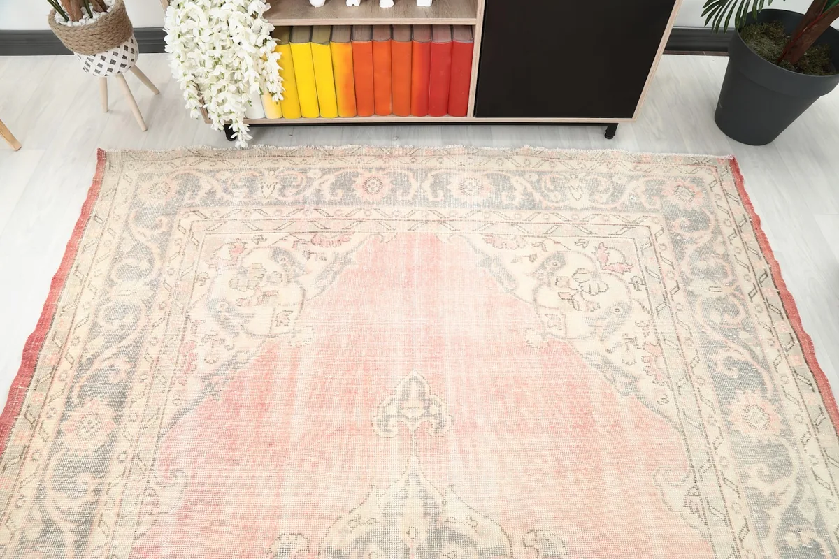 Overhead view of one end of the rose and gray rug, highlighting the border design