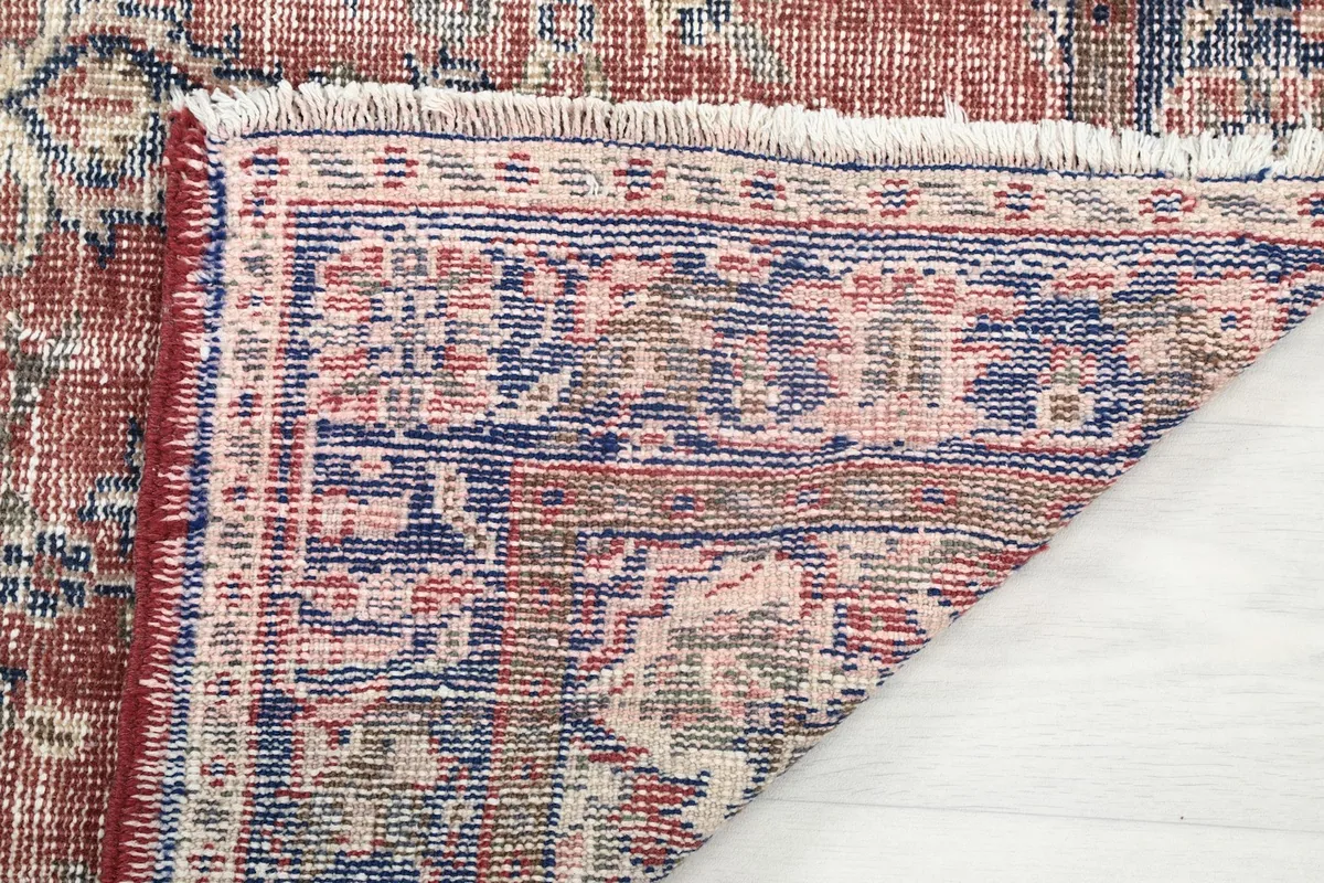 Close-up of the rug's back and fringe, showing the wool pile on cotton foundation