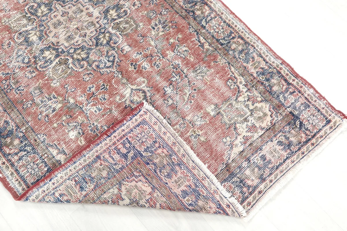 View of the rug folded back, revealing the underside and the hand-knotted construction